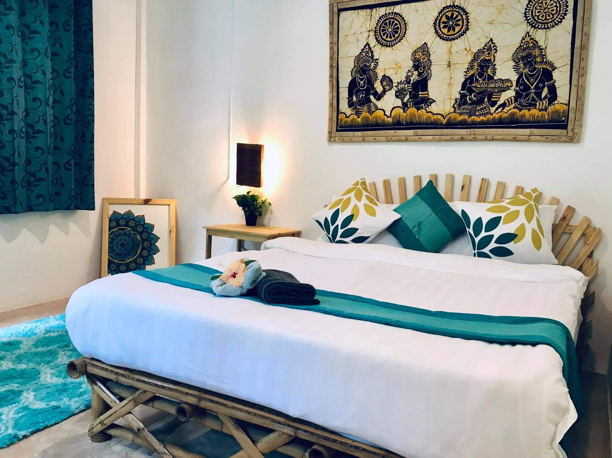 Inside a bungalow: a double bed with teal cushions
